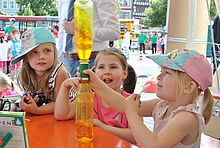 Drei Mädchen bestaunen eine Strudelbildung in einer Flasche.