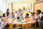 Bundeskanzlerin Angela Merkel sitzt gemeinsam mit Kindern und Erzieherinnen an einem Basteltisch