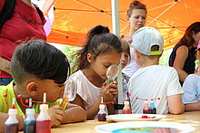 Kinder untersuchen Farbtuben mit einer Lupe