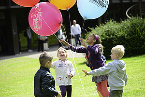 Kinder mit bunten Luftballons auf einer Wiese