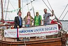 Vier Erwachsene auf einem Schiff mit einem Banner des Schulforschungsschiffes Louisenlund