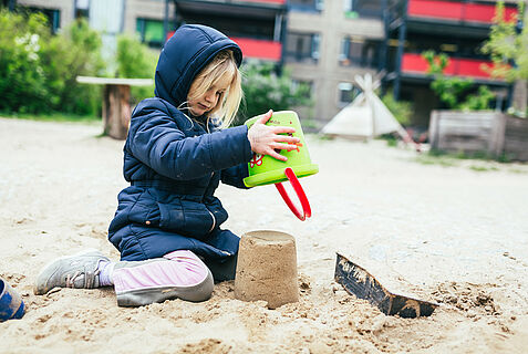 Ein Kind baut eine Sandburg