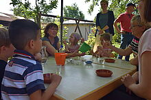 Die niedersächsische Kultusministerin Frauke Heiligenstadt sitzt mit Kindern und Erzieherinnen am Tisch und untersucht verschiedene Materialien