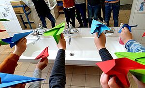 Kinder halten bunte Papierflieger in den Händen