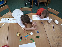 ZWei Jungen forschen mit verschiedenen Materialien an einem Tisch