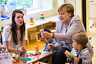 Bundeskanzlerin Angela Merkel bastelt gemeinsam mit Kindern und Erzieherinnen an einem Tisch